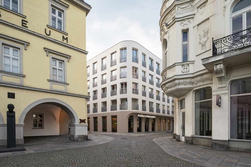 Domovní blok vymezený ulicemi Velkou, Pivovarskou, Muzejní a Dlouhou se nachází ve středověkém jádru města; původní zástavbu – tzv. Lauby – zde tvořilo šest parcel s měšťanskými domy.