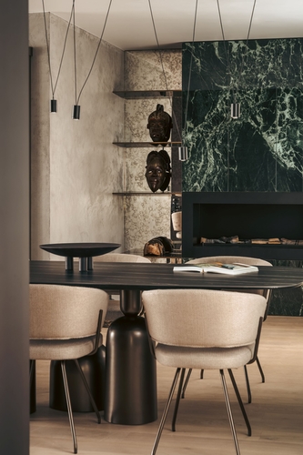 Ze stran je krb doplněn mosaznými policemi, za nimiž je obklad ze stařeného zrcadla.