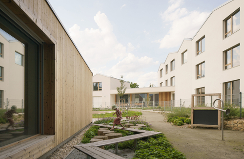 Klíčovým prostorem pro interakci mezi dětmi a seniory je zahrada; herní prvky jsou převážně přírodního charakteru – zatravněné valy, vyvýšené dřevěné lávky mezi bylinkami, vodní koryto s malými hrázemi.