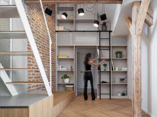 Celou jednu stěnu v obytném prostoru zaujímá knihovna s netradičním posuvným žebříkem.